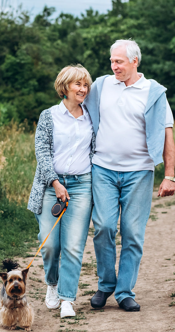 Happy Retired Couple Walking Dog on Trail